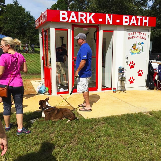 People lined up outside of the pet wash at the dog park waiting for their turn with their dogs.