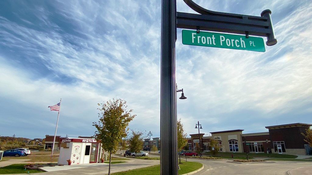 a green street sign for front porch pl with a pet washing station in the back